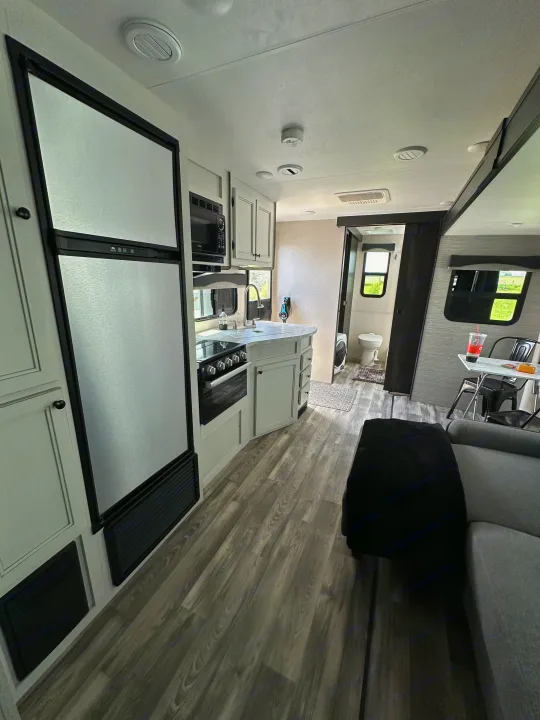 Modern RV rental interior showcasing a compact kitchen, living space, and bathroom. Well-lit and functional.. Highland Ridge RV Open Range 2022
