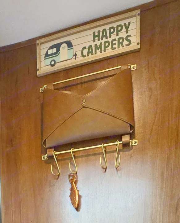 RV rental interior: 'HAPPY CAMPERS' sign, brown organizer, and hooks with a fish opener on a wood wall. Great for travel essentials!. Jayco Jay Feather 7 XRB 2016