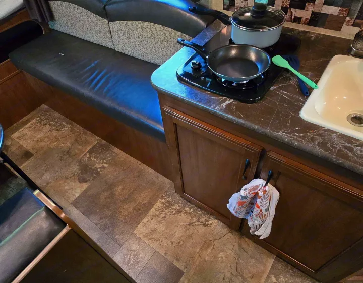 RV rental interior: Compact kitchenette with cooktop & sink, plus dinette seating, all on patterned tile flooring.. Jayco Jay Feather 7 XRB 2016
