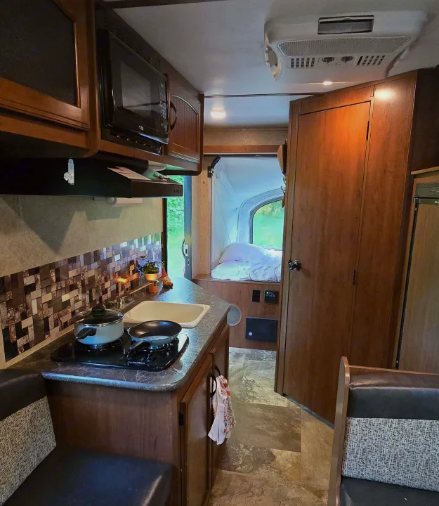 Spacious RV rental interior with a modern kitchen, microwave, comfy seating, and a cozy bedroom in the rear.. Jayco Jay Feather 7 XRB 2016