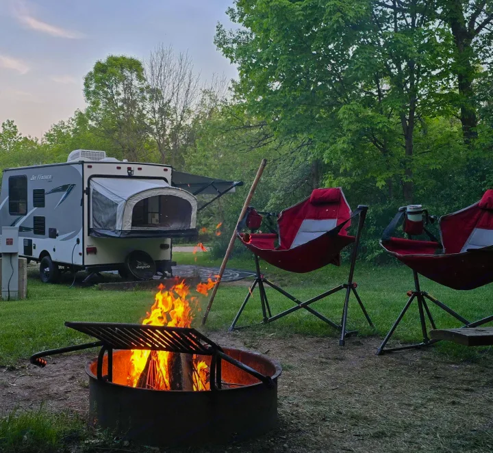 RV rental camping adventure: a Jay Feather trailer, crackling campfire, and red chairs in a wooded setting.. Jayco Jay Feather 7 XRB 2016