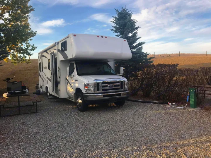 This Sunseeker RV rental is set up at a scenic gravel campsite with utility hookups and a picnic table.. Forest River Sunseeker 2008