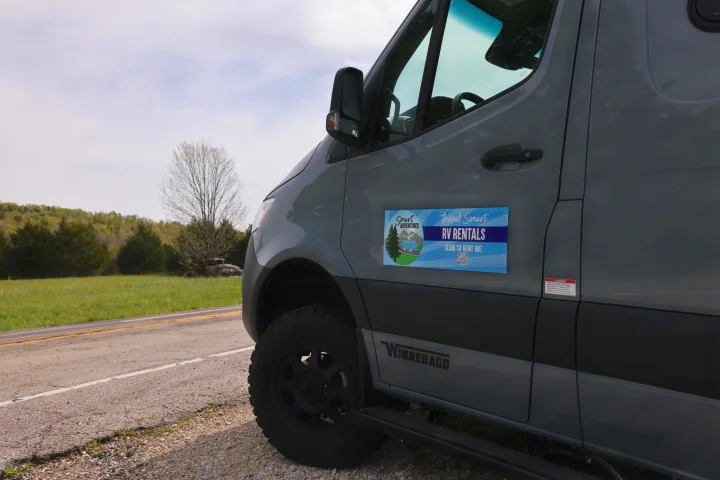 Grey Winnebago RV rental parked roadside. Features "Travel Smart RV Rentals" magnet. Perfect for outdoor adventures.. Mercedes Winnebago Revel 2023