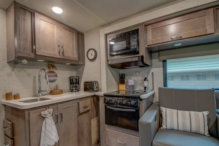 Cozy RV rental kitchen featuring modern appliances, a sink, stove, and comfortable dinette seating for travel.. Winnebago Minnie Winnie 2021