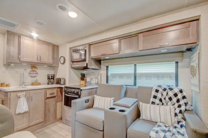 Spacious RV rental interior featuring a well-equipped kitchen with stove, microwave, and cozy recliners.. Winnebago Minnie Winnie 2021