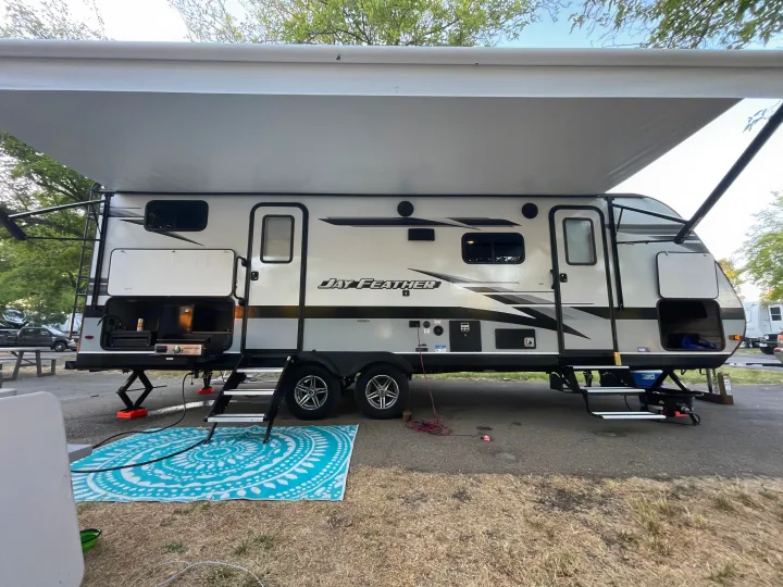 Jay Feather rv rental set up for camping: extended awning, outdoor kitchen, steps, and a turquoise mat.. Jayco Jay Feather 2022