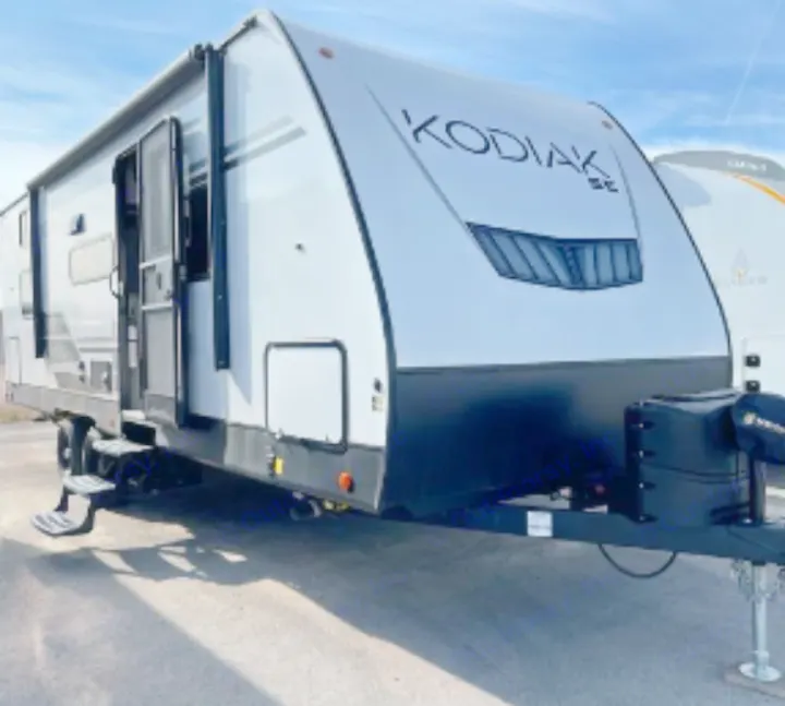 "KODIAK SE" travel trailer, a spacious white RV for rental. Features include an extended entry door and steps, ideal for outdoor recreation.. Dutchmen Kodiak SE 2023