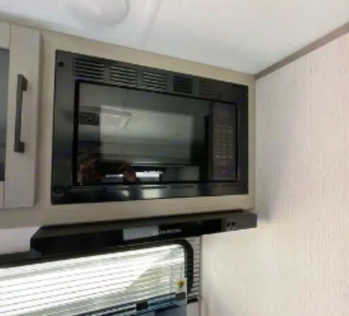 Sleek, black built-in microwave and range hood in an RV rental kitchen, offering essential cooking appliances.. Dutchmen Kodiak SE 2023