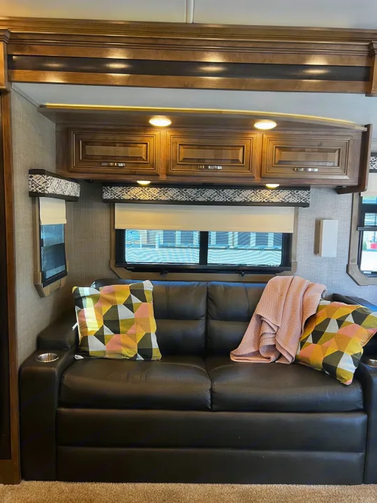 Relax in this comfortable rv rental living area. Features black sofa, modern cabinets, and lighted interior for your journey.. Jayco Seneca 2021