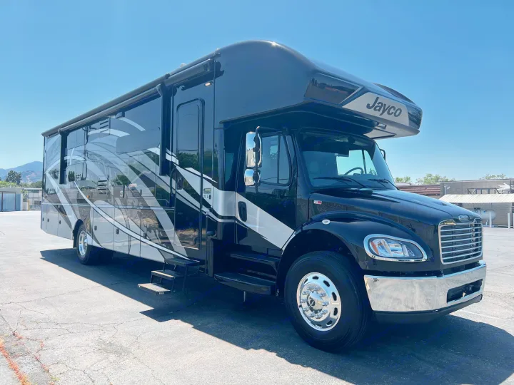 Jayco Super C RV rental: A large black motorhome with sleek graphics & chrome, built on a Freightliner chassis, parked outdoors.. Jayco Seneca 2021