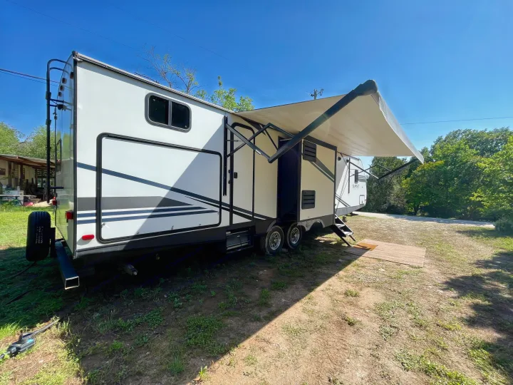 This clean white RV rental travel trailer, with its awning out, is ready for a peaceful outdoor retreat or adventure.. Crossroads RV Sunset Trail Super Lite 2019