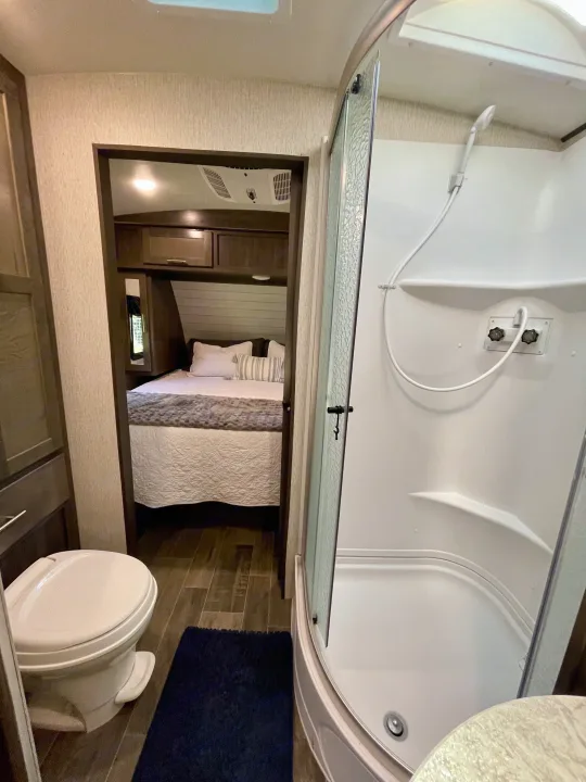 RV rental interior showcasing a compact bathroom with shower and toilet, and a cozy bedroom beyond.. Crossroads RV Sunset Trail Super Lite 2019