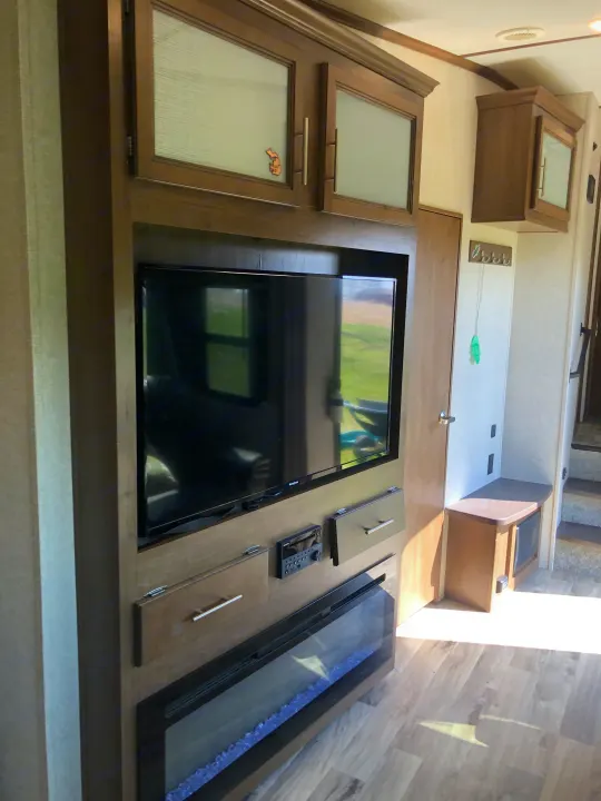 Modern RV rental living space featuring a TV, entertainment system, and electric fireplace. Stay comfortable on the road.. Keystone RV Cougar 2020
