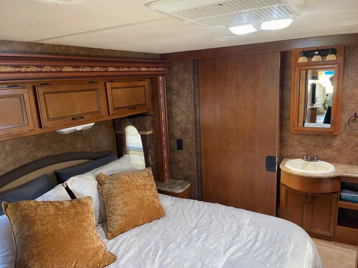 Comfortable RV rental bedroom with a private sink, mirror, and storage cabinets for your travels.. Thor Hurricane 2014