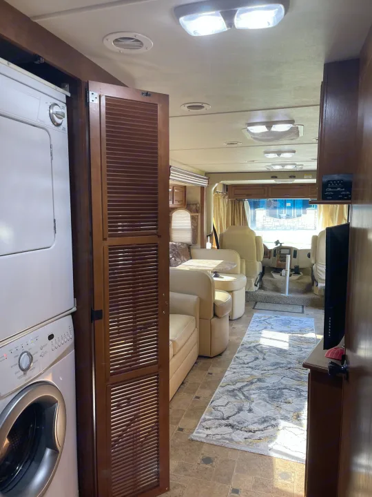 Inside this RV rental: A stacked washer/dryer and a bright living area leading to the driver's cockpit.. Thor Hurricane 2014