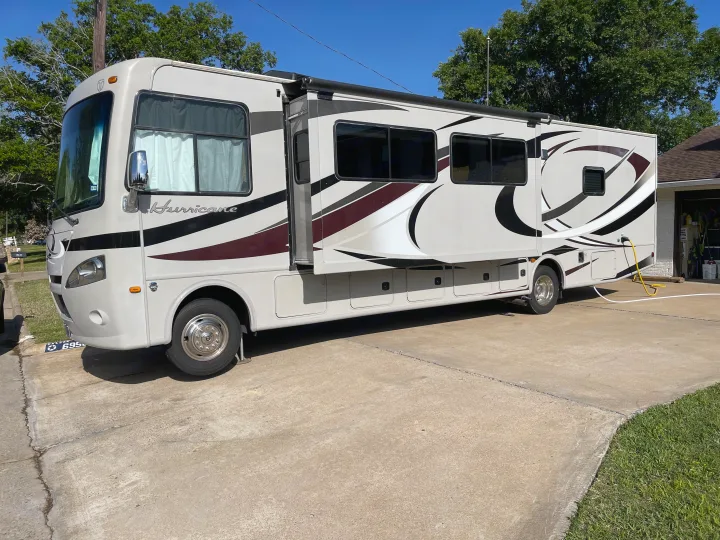 Cream-colored Hurricane RV rental motorhome parked on concrete driveway with side expanded.. Thor Hurricane 2014
