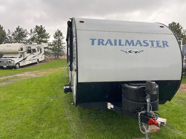 TRAILMASTER travel trailer (RV rental) at a grassy campground. A Jayco motorhome is visible in the background.. Gulf Stream Trailmaster 2018