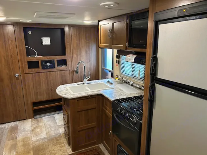 Spacious RV rental interior featuring a full kitchen with stove, microwave, fridge, sink, and entertainment area.. Gulf Stream Trailmaster 2018