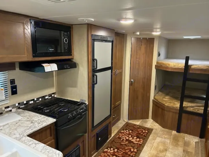 This RV rental features a full kitchen with microwave, stove, and fridge, plus comfortable bunk beds.. Gulf Stream Trailmaster 2018