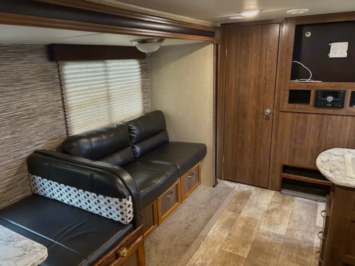 RV rental's inviting living space: black leather dinette, pleated blinds, and wood-grain cabinetry with entertainment area.. Gulf Stream Trailmaster 2018