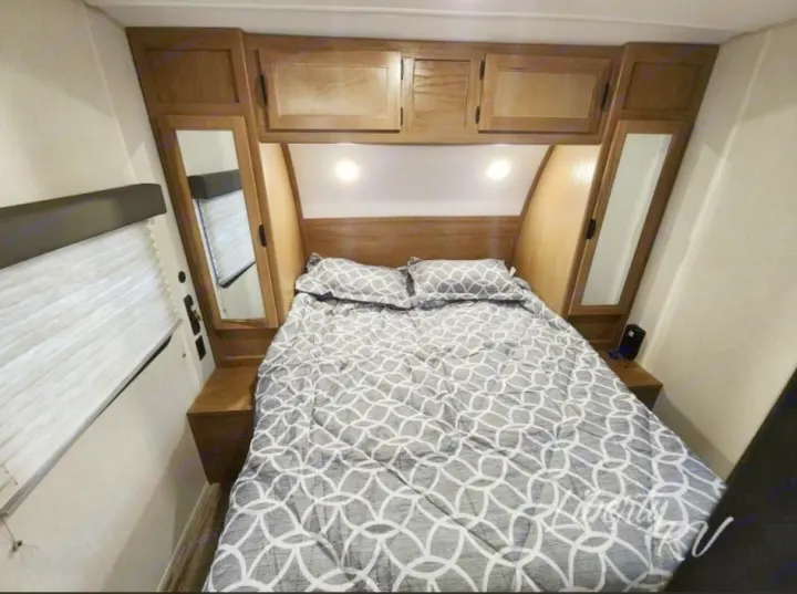 RV rental master bedroom featuring a comfortable bed, overhead cabinets, and built-in nightstands.. Forest River Cherokee Grey Wolf 2024