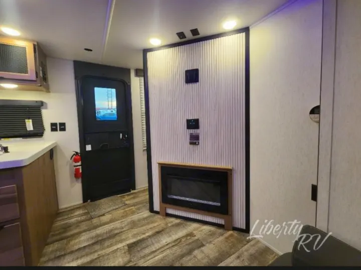 Rv rental interior: kitchen, main door, wall with fireplace & controls. Comfortable living space for your adventure.. Forest River Cherokee Grey Wolf 2024