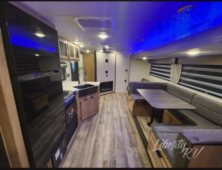 RV rental: Modern interior with full kitchen, U-shaped dinette, and blue ambient lighting. Ideal for comfortable travel.. Forest River Cherokee Grey Wolf 2024