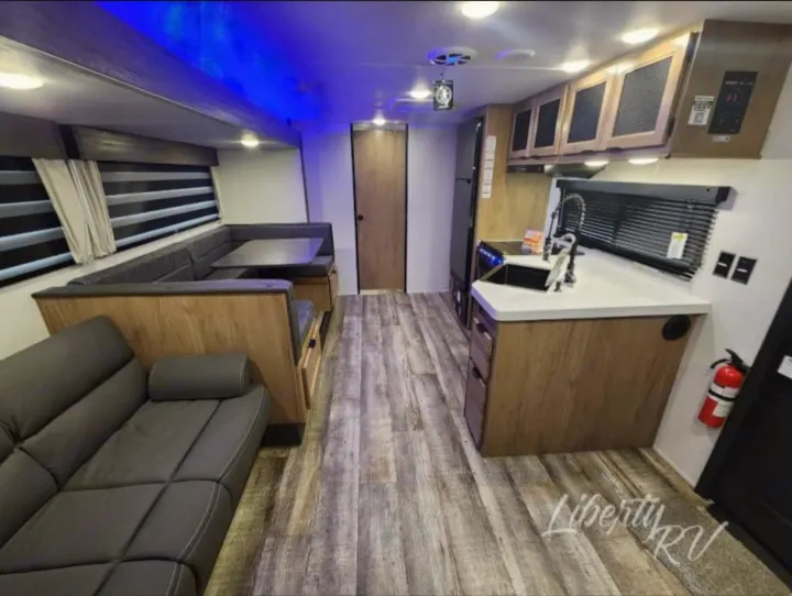 An RV rental's spacious interior, showcasing a living area with a sofa, a U-shaped dinette, and a kitchen with a sink.. Forest River Cherokee Grey Wolf 2024