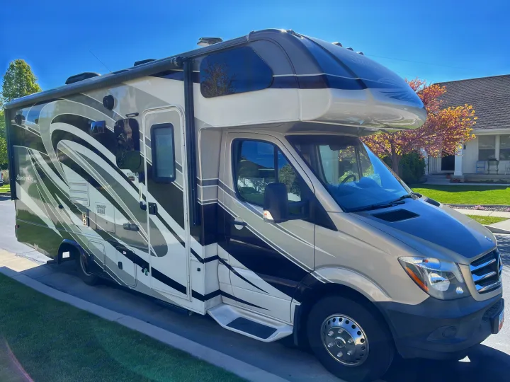 This modern, light-colored Class C RV rental with bold graphics, parked on a sunny street, is ready for your next adventure.. Forest River Sunseeker MBS 2016