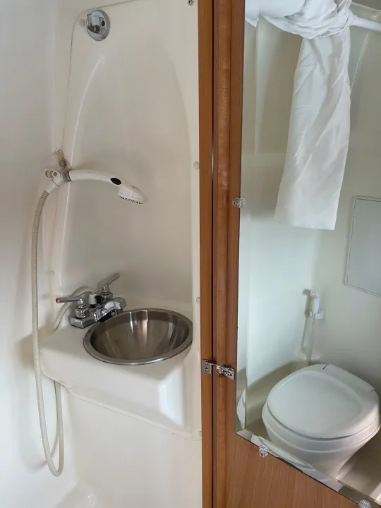Compact RV rental wet bath featuring a handheld shower, sink, and toilet, ideal for travel.. Winnebago Era 2010