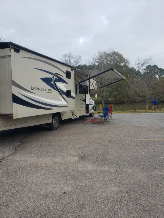 RV rental: A beige Leprechaun Coachmen motorhome parked by a river with its awning out, ready for a relaxed day.. Forest River Coachmen Leprechaun 2015