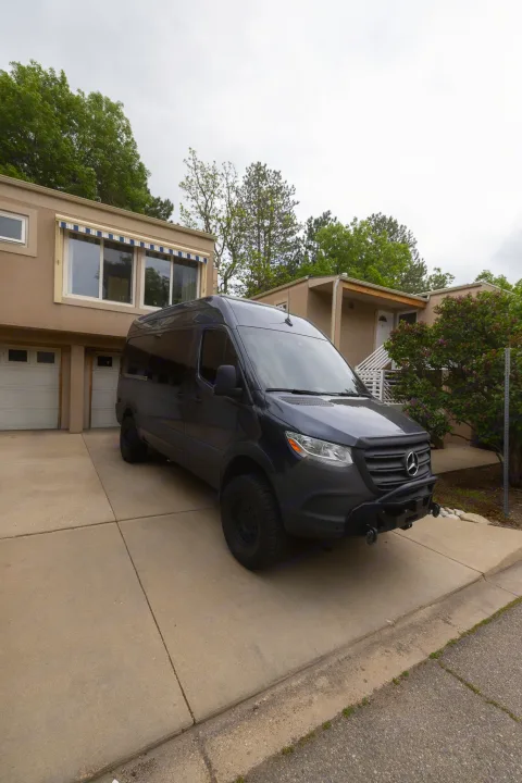 A sleek, dark grey Mercedes-Benz Sprinter van, often used as an RV rental, parked on a residential driveway.. Mercedes Sprinter 2500 2024