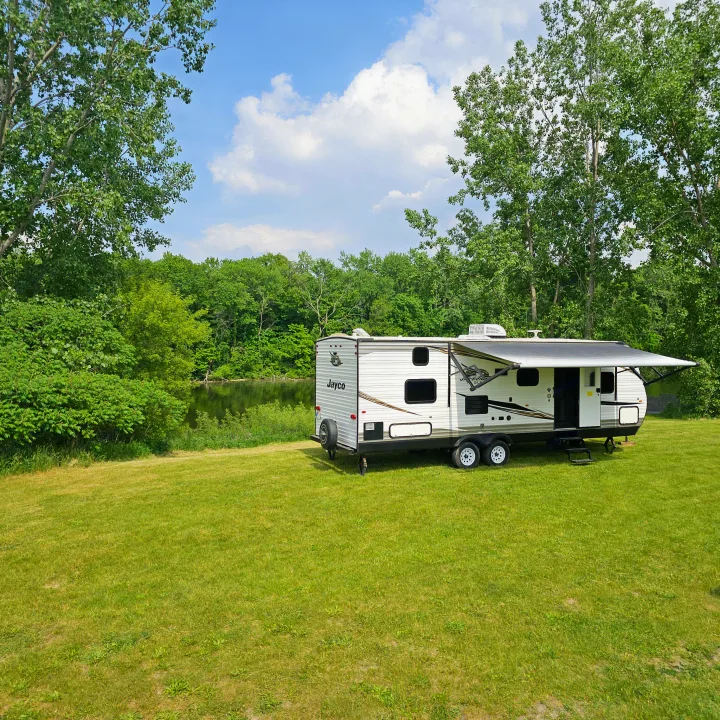 Experience tranquil camping with this rv rental! A Jayco travel trailer by a peaceful lake, surrounded by lush greenery.. Jayco Jay Flight SLX8 2020