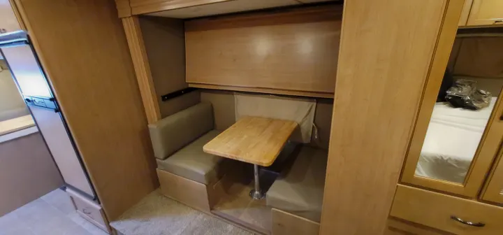 RV rental interior: cozy dinette with convertible bunk, compact kitchen with fridge, and mirrored wardrobe.. Thor Chateau 2018