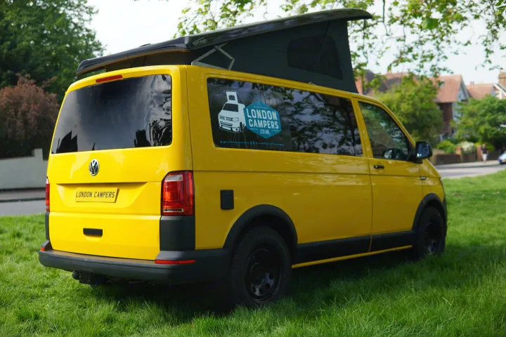 Bright yellow London Campers VW campervan with a pop-top roof, ready for rv rental on green grass.. Volkswagen T6 2017