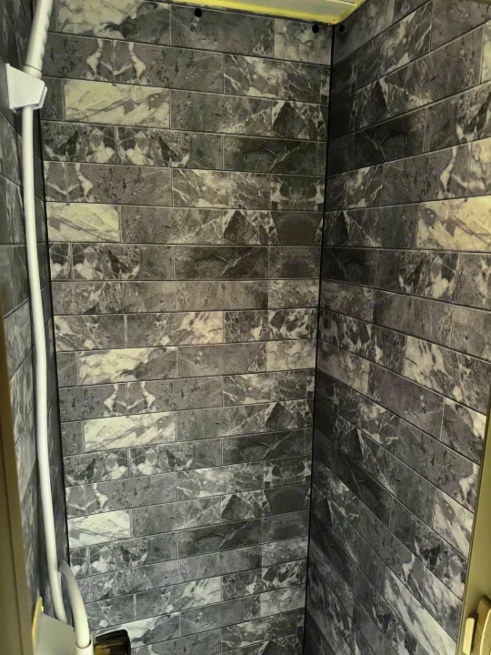 Modern grey & white marble-look tiled shower interior in an RV rental, featuring a white shower rail.. Braxton Creek Bushwhacker Plus 2022