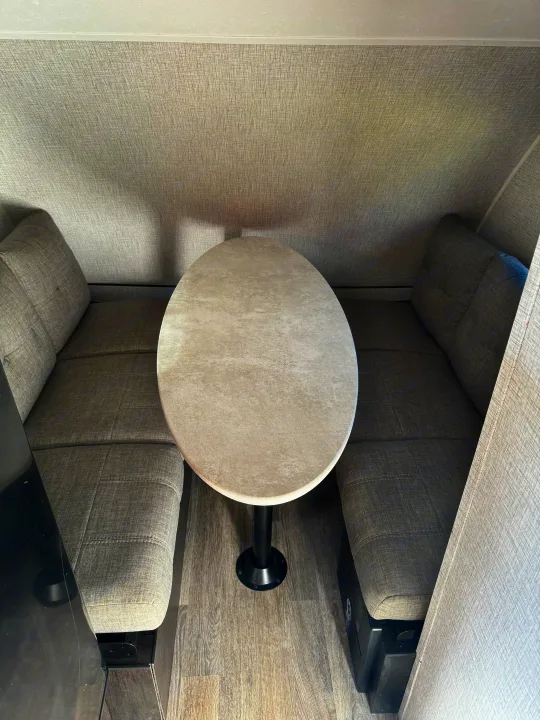 Cozy RV rental dinette with grey upholstered benches, an oval table, and wood-look flooring.. Braxton Creek Bushwhacker Plus 2022