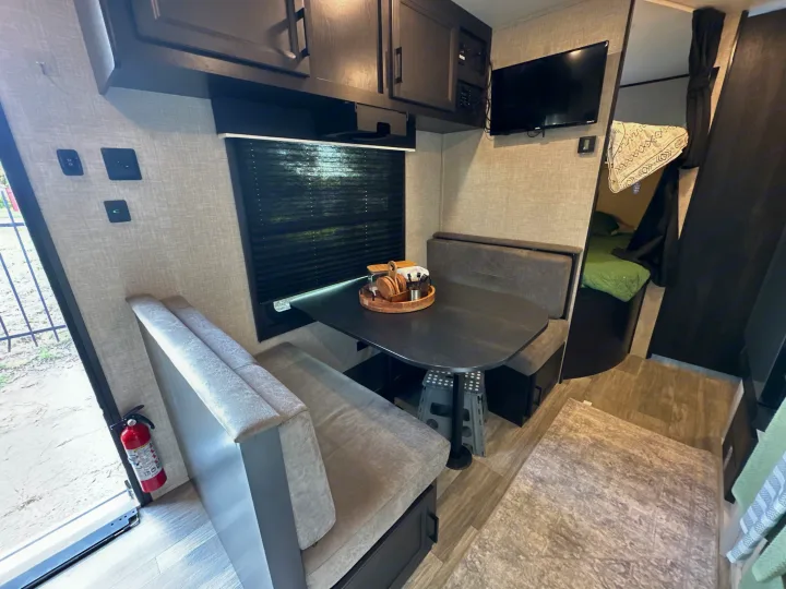 Spacious RV rental interior featuring a modern dinette, TV, and cozy sleeping area, ideal for travel adventures.. Jayco Jay Flight 2023