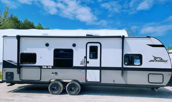 Jayco Jay Flight SLX travel trailer, a white and grey RV ideal for rv rental adventures, featuring an awning and dual axles.. Jayco Jay Flight SLX 2024