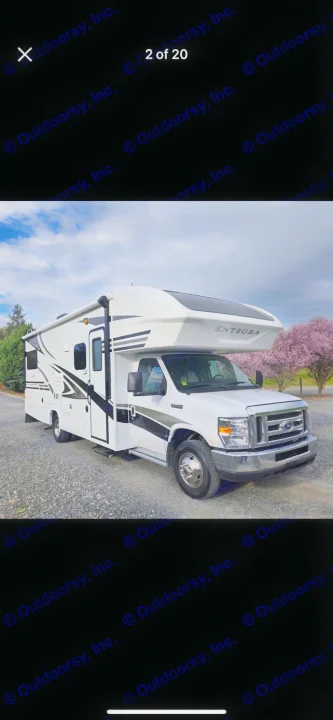 White Entegra Class C motorhome rv rental parked on gravel. Features sleek graphics, perfect for road trips & adventures.. Entegra Coach Odyssey 2019