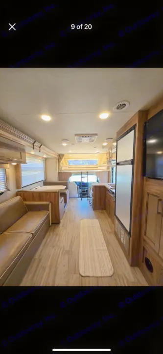 Spacious RV rental interior featuring a clean living area with sofa, dinette, kitchen, and overhead bunk.. Entegra Coach Odyssey 2019