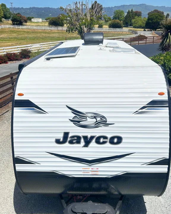 Front view of a white Jayco travel trailer with a solar panel on top, ideal for rv rental adventures in scenic landscapes.. Jayco Jay Flight 2023