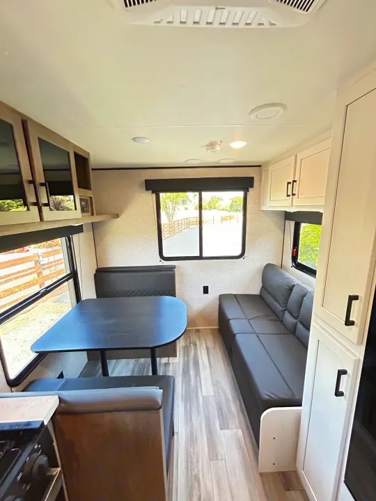 Bright and modern RV rental interior featuring a dinette, sofa, and compact kitchen, ideal for travel adventures.. Jayco Jay Flight 2023