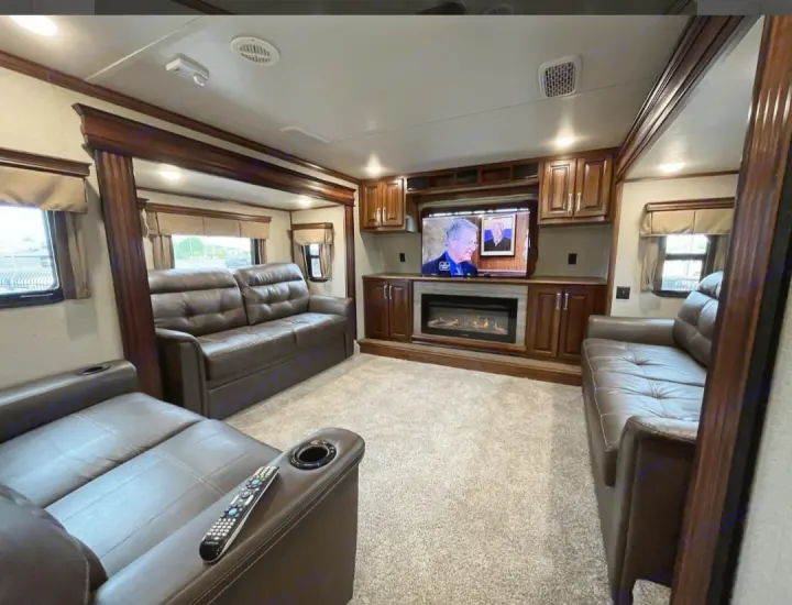 Experience luxury RV rental travel in this living room featuring two leather couches, TV, fireplace, and rich wood details.. Keystone RV Alpine 2018