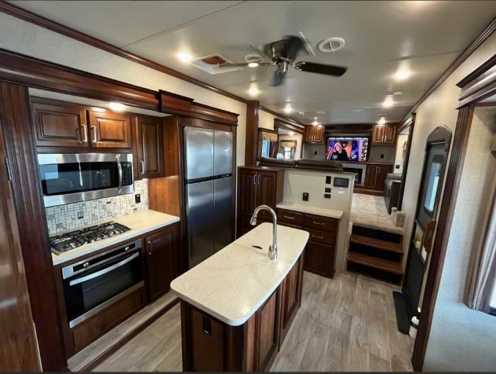 Luxurious RV rental interior: fully-equipped kitchen with stainless appliances, island, & living area via steps.. Keystone RV Alpine 2018