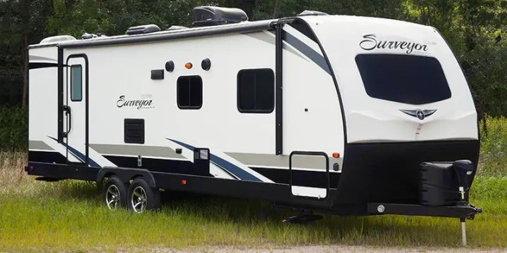Spacious white Surveyor travel trailer, an excellent option for an RV rental getaway, parked in nature.. Forest River Surveyor Legend 2019