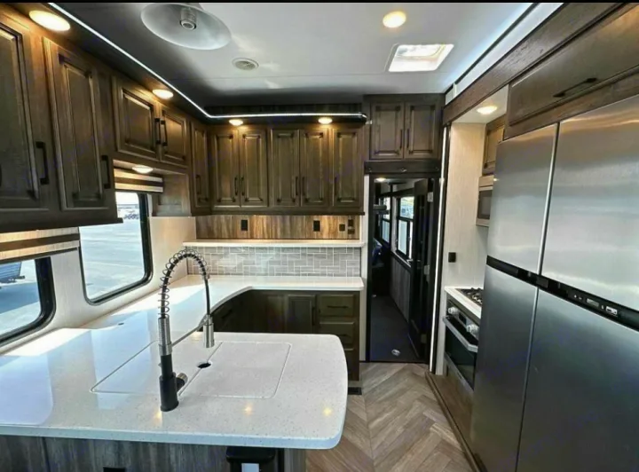 Spacious, bright RV rental kitchen featuring stainless steel appliances, sleek dark cabinets, and ample counter space.. Heartland Cyclone 2022