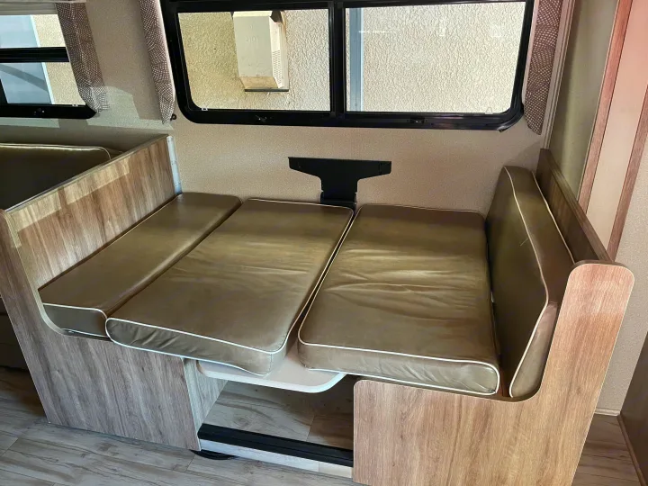 RV rental interior: Convertible dinette with brown cushions & white piping, ready to transform into a bed.. Entegra Coach Odyssey 2019