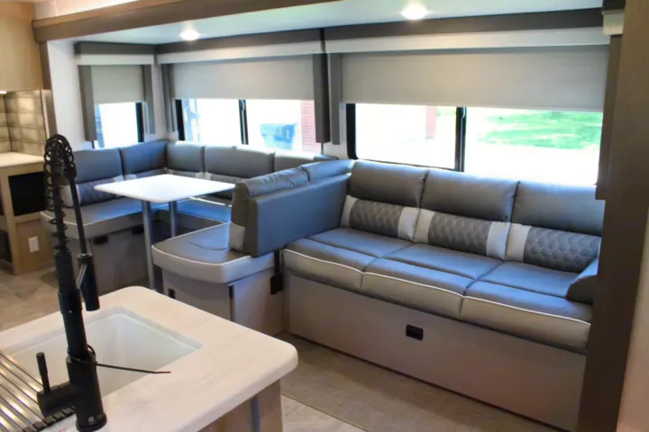 Spacious RV rental interior featuring a gray dinette, comfortable sofa, and kitchen sink. Ideal for travel.. Forest River Wildwood Platinum 2024