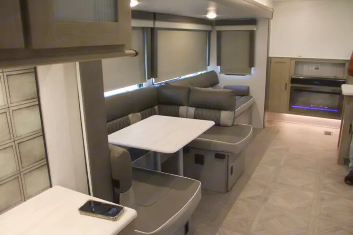 Spacious RV rental interior featuring a modern U-shaped dinette, dining table, and cozy electric fireplace.. Forest River Wildwood Platinum 2024